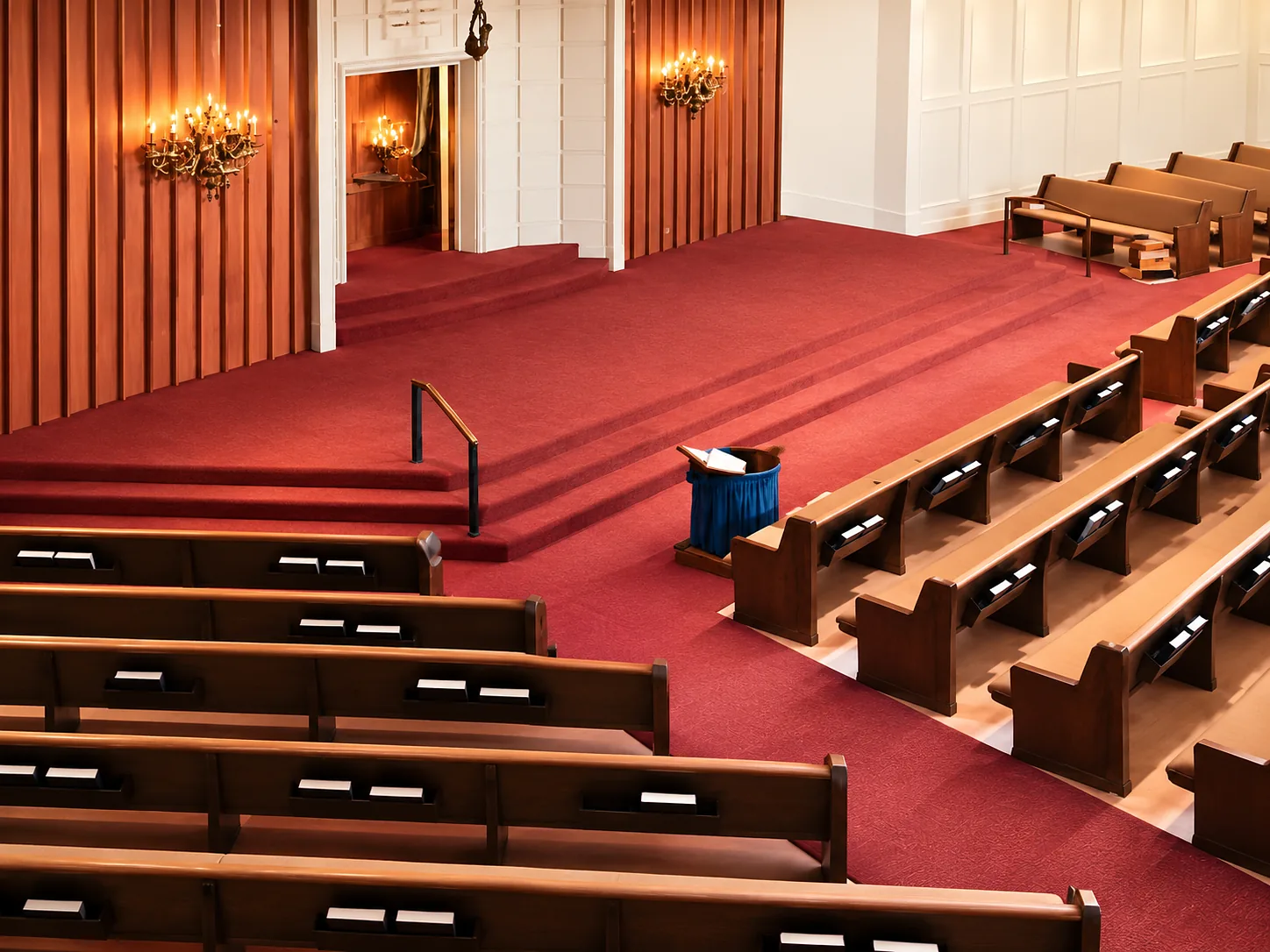 Church sanctuary with wooden pews and a broad carpeted platform and steps in deep red carpet